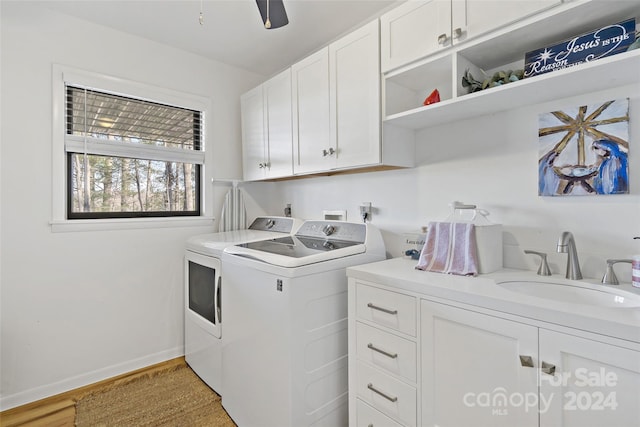 clothes washing area featuring ceiling fan, sink, cabinets, washer and dryer, and light wood-type flooring