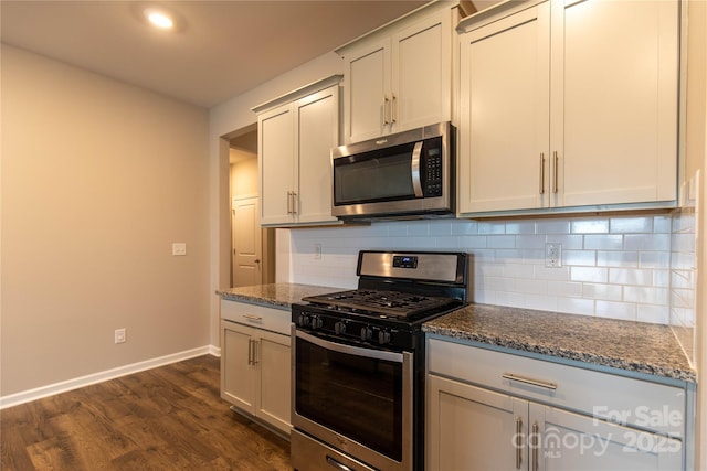 kitchen featuring tasteful backsplash, appliances with stainless steel finishes, stone countertops, and dark hardwood / wood-style flooring