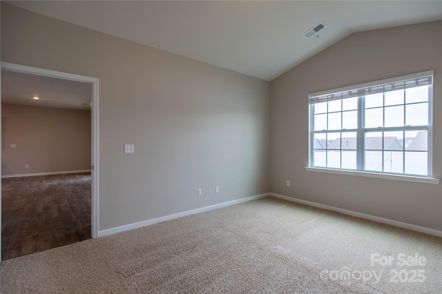 carpeted empty room featuring vaulted ceiling