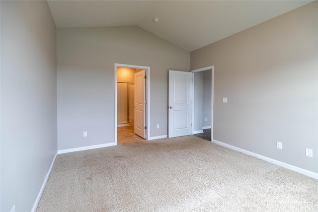 unfurnished bedroom with vaulted ceiling and light carpet