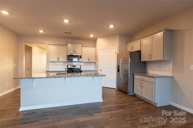 kitchen with stone countertops, visible vents, dark wood-style flooring, and stainless steel appliances