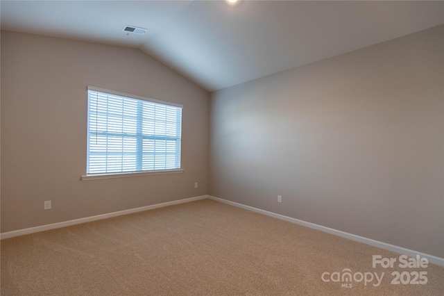 empty room featuring lofted ceiling, baseboards, visible vents, and light carpet