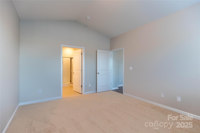 unfurnished bedroom featuring baseboards, carpet, lofted ceiling, and ensuite bathroom