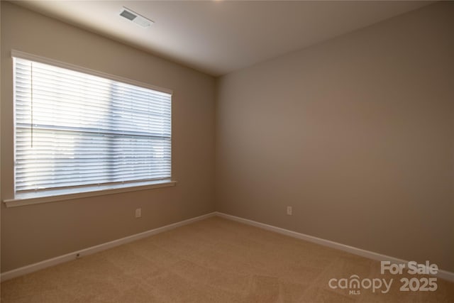 unfurnished room with baseboards, visible vents, and light carpet