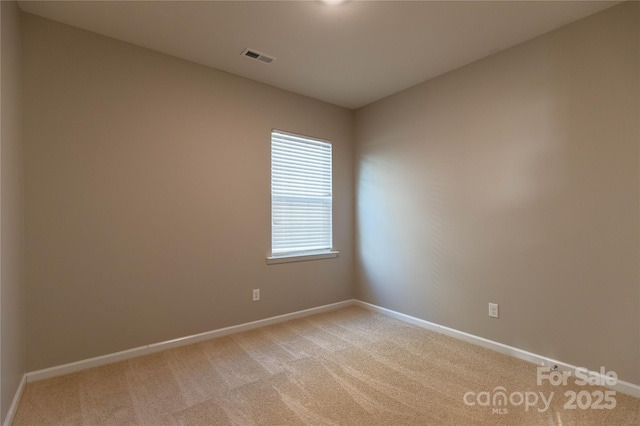 empty room featuring baseboards, light carpet, and visible vents