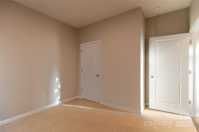 unfurnished room with light colored carpet and baseboards