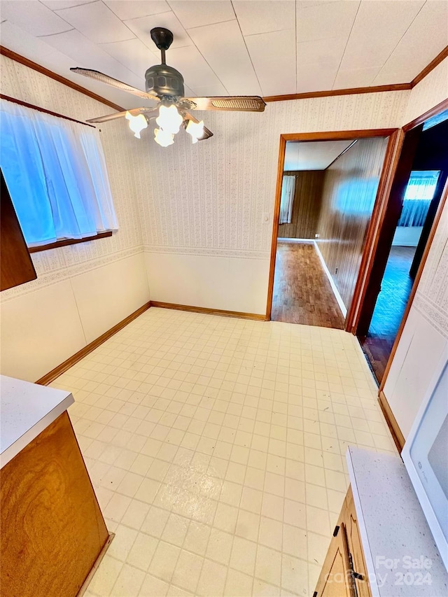 unfurnished dining area featuring ceiling fan, light wood-type flooring, and ornamental molding