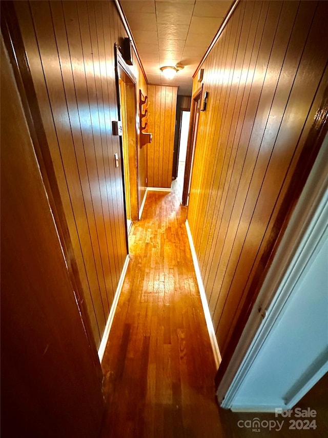 hall with wooden walls and hardwood / wood-style flooring