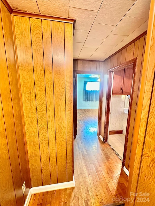 hall featuring wooden walls and light hardwood / wood-style flooring