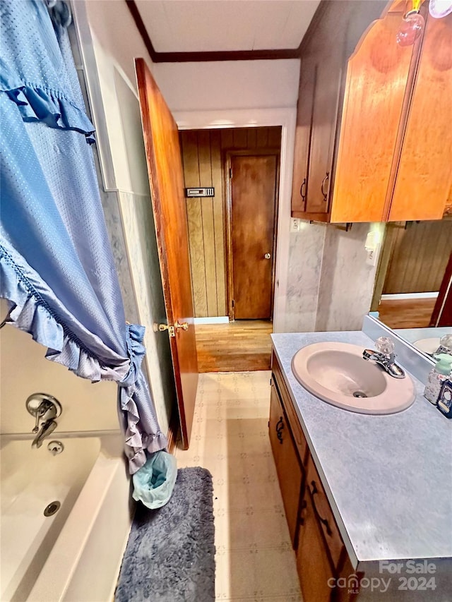 bathroom with hardwood / wood-style flooring, vanity, crown molding, and a tub to relax in