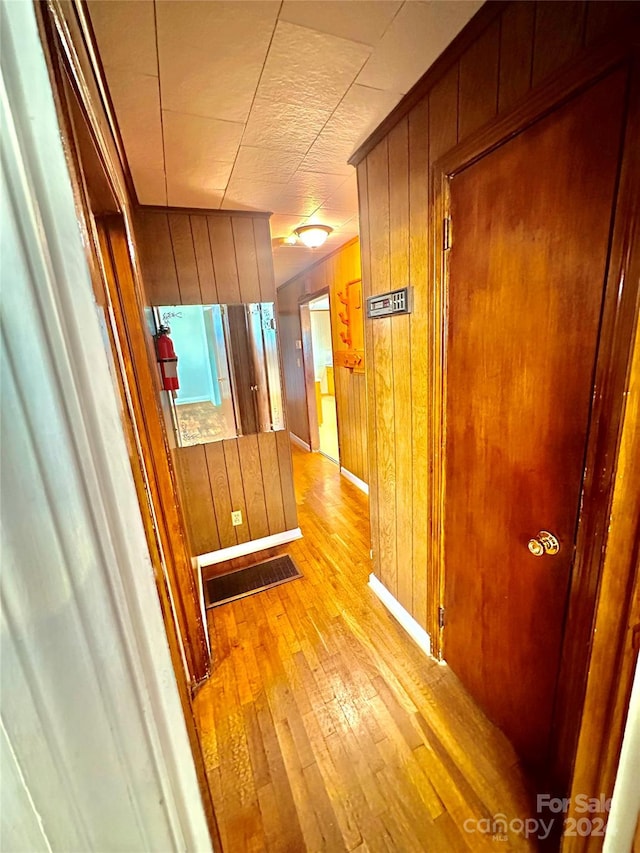 hallway with wood walls and light hardwood / wood-style floors