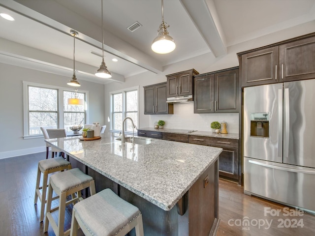 kitchen with a kitchen island with sink, sink, beamed ceiling, and stainless steel refrigerator with ice dispenser