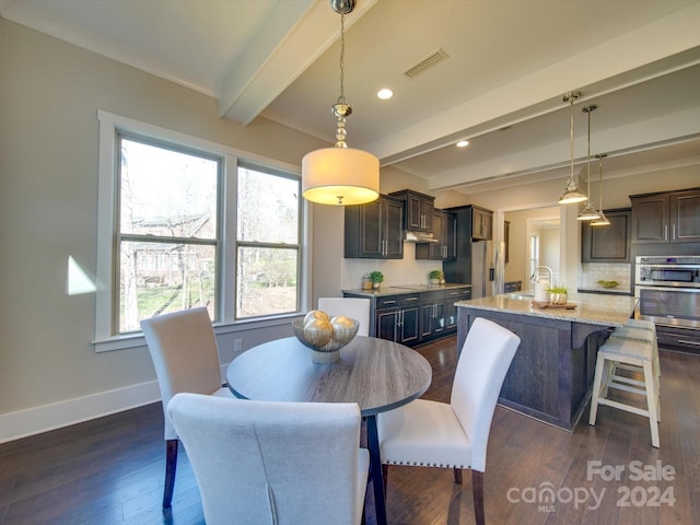 dining area with dark hardwood / wood-style floors, beam ceiling, ornamental molding, and sink