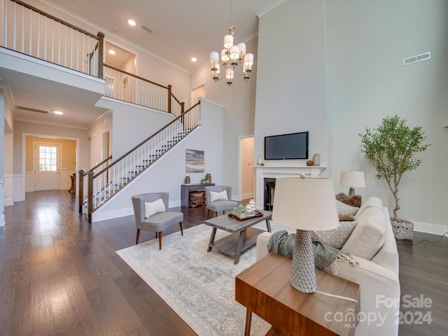 living room with a high ceiling, dark hardwood / wood-style flooring, ornamental molding, and a notable chandelier