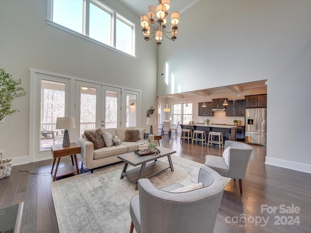 living room with a chandelier, a high ceiling, dark hardwood / wood-style flooring, and french doors