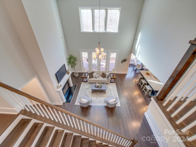 living room featuring french doors, a towering ceiling, dark hardwood / wood-style floors, and a notable chandelier