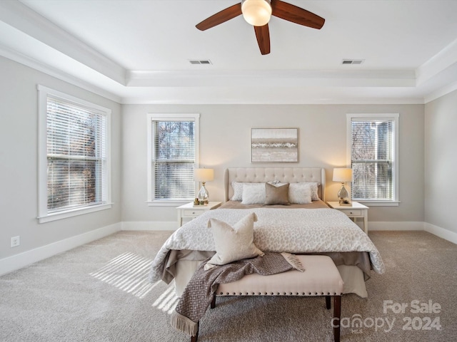 carpeted bedroom with ceiling fan, a raised ceiling, and crown molding