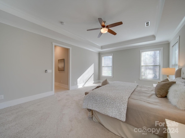 bedroom featuring ceiling fan, a raised ceiling, and light carpet