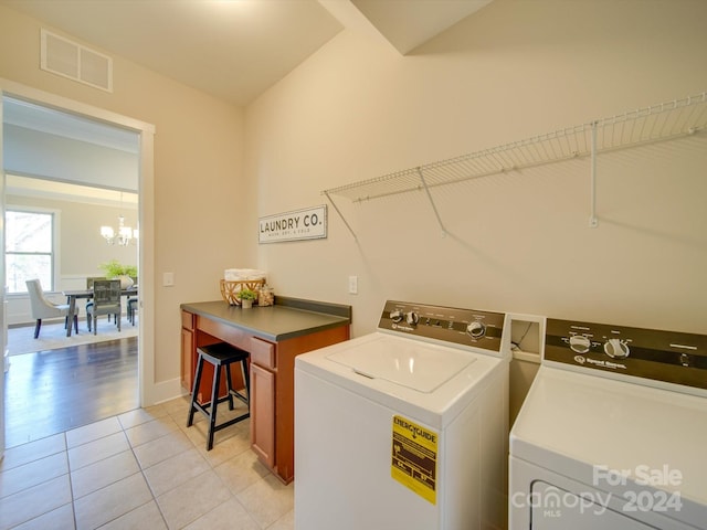 clothes washing area featuring a notable chandelier, washing machine and dryer, and light tile patterned floors