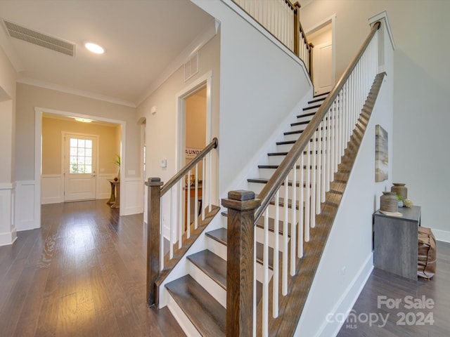 stairs featuring wood-type flooring and crown molding