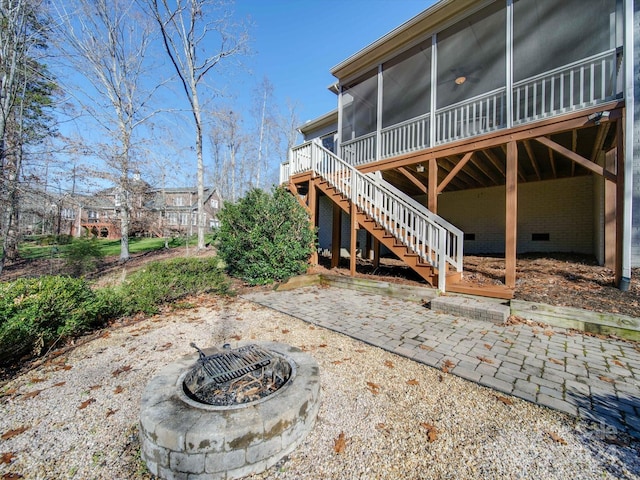 rear view of house with a fire pit, a patio area, and a sunroom