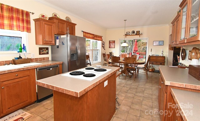 kitchen featuring sink, ornamental molding, decorative light fixtures, a kitchen island, and stainless steel appliances