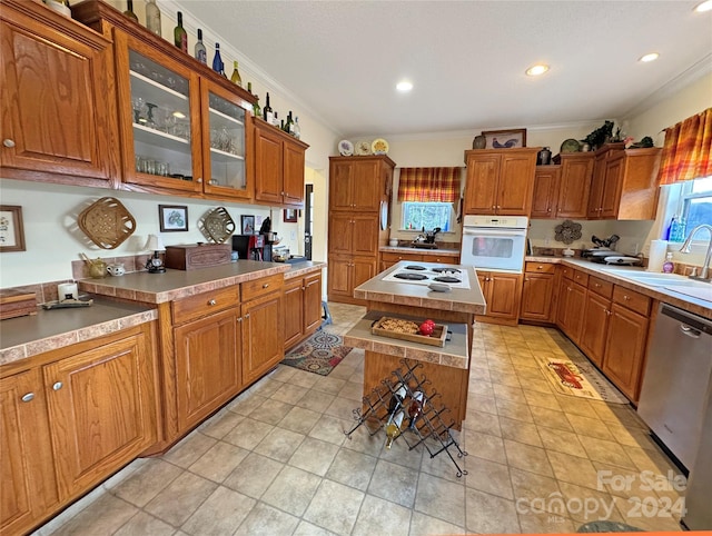 kitchen with white appliances, a kitchen island, crown molding, and sink