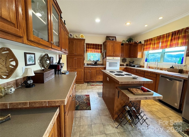 kitchen with a center island, white appliances, sink, crown molding, and a breakfast bar area