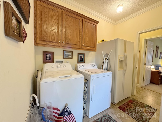 washroom featuring cabinets, crown molding, washing machine and dryer, light tile patterned floors, and a textured ceiling