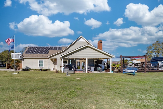 rear view of property with solar panels, a patio, and a lawn