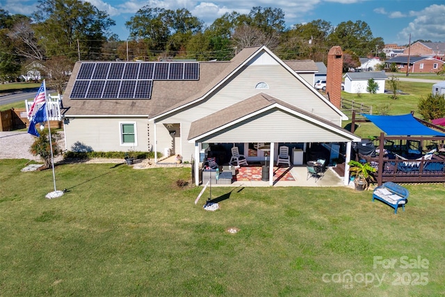 rear view of house featuring solar panels, a patio, an outdoor hangout area, and a lawn