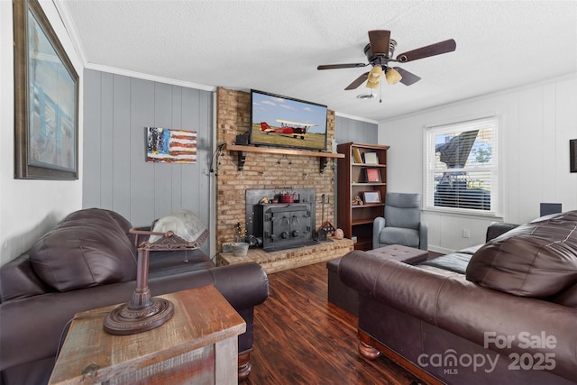 living room featuring a wood stove, dark hardwood / wood-style floors, ceiling fan, ornamental molding, and a textured ceiling