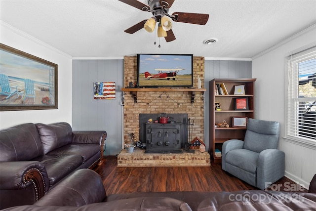 living room featuring a textured ceiling, wooden walls, crown molding, dark hardwood / wood-style floors, and a wood stove