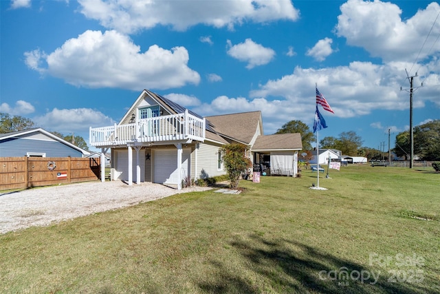 view of front of home with a wooden deck, a front yard, and a garage