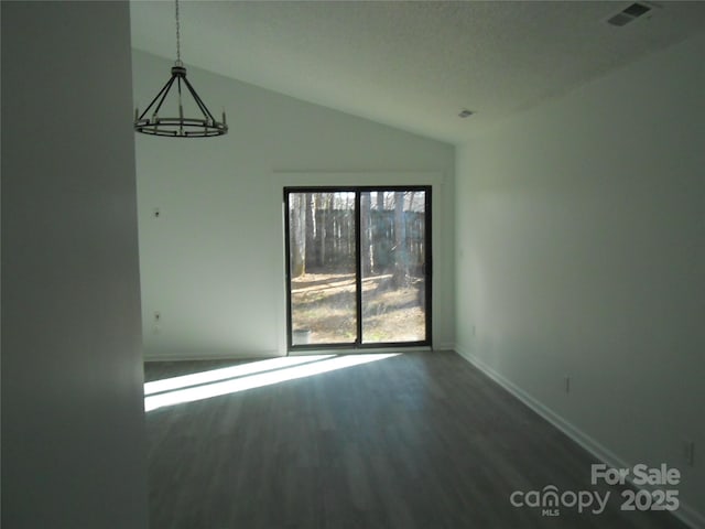 unfurnished room with visible vents, an inviting chandelier, vaulted ceiling, wood finished floors, and baseboards