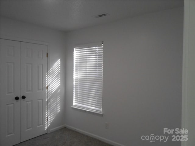 unfurnished bedroom featuring a closet, carpet flooring, visible vents, and baseboards