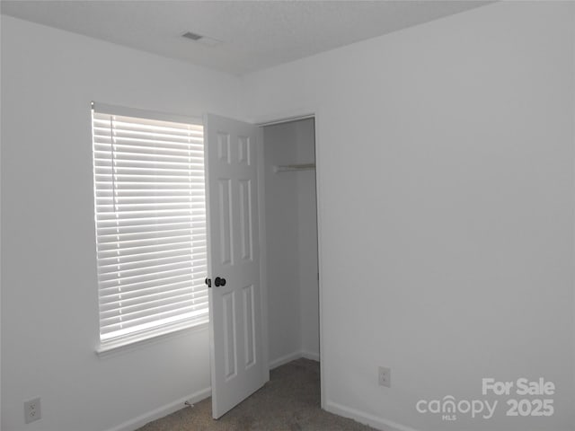 unfurnished bedroom featuring carpet floors, a closet, visible vents, a spacious closet, and baseboards