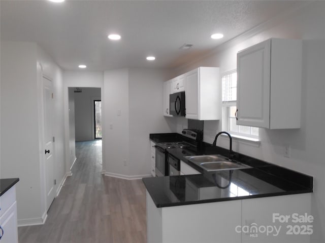 kitchen featuring dark countertops, range with electric cooktop, black microwave, and a sink