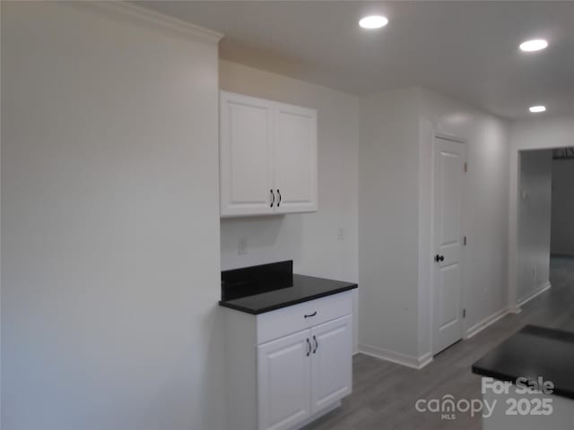 interior space with recessed lighting, dark countertops, white cabinets, wood finished floors, and baseboards