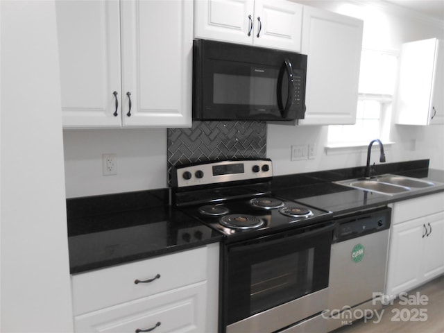 kitchen with dark countertops, white cabinetry, appliances with stainless steel finishes, and a sink