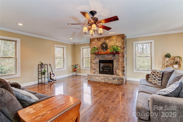 living room featuring hardwood / wood-style floors, ceiling fan, ornamental molding, and a fireplace