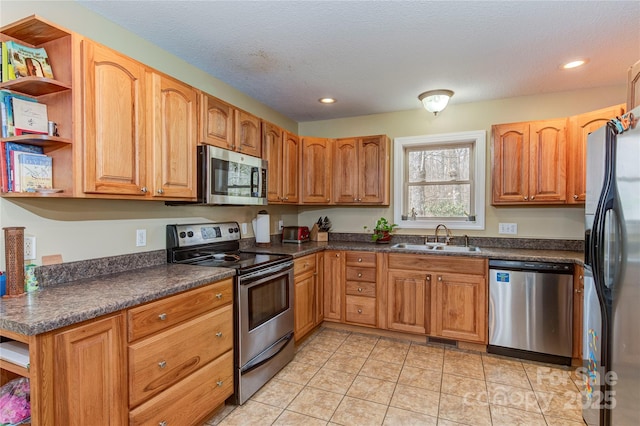 kitchen with sink, light tile patterned flooring, stainless steel appliances, and a textured ceiling