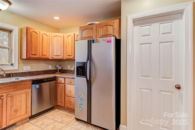 kitchen featuring sink, light tile patterned flooring, stainless steel appliances, and a textured ceiling