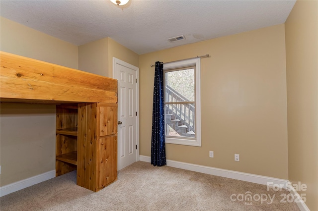 unfurnished bedroom featuring light carpet and a textured ceiling