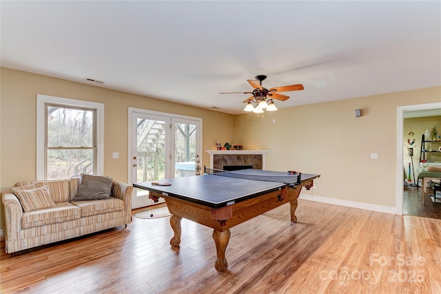 playroom featuring a fireplace, light wood-type flooring, and ceiling fan