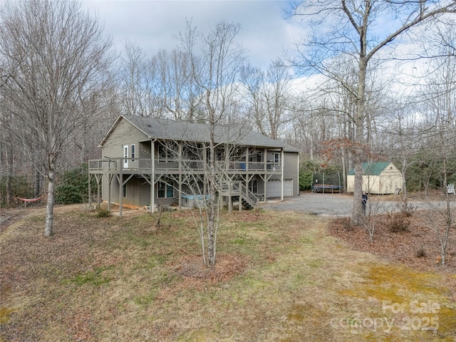 back of house with a deck, a trampoline, and a shed