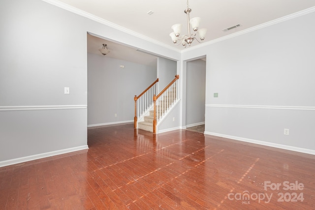 empty room with hardwood / wood-style floors, crown molding, and an inviting chandelier