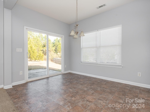 unfurnished room with a notable chandelier