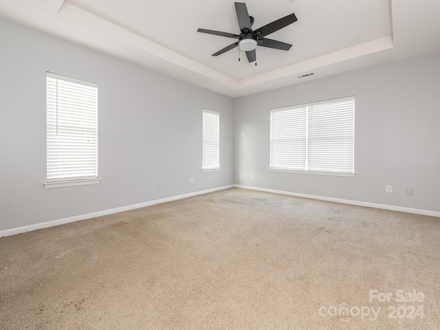 carpeted empty room featuring a raised ceiling and ceiling fan