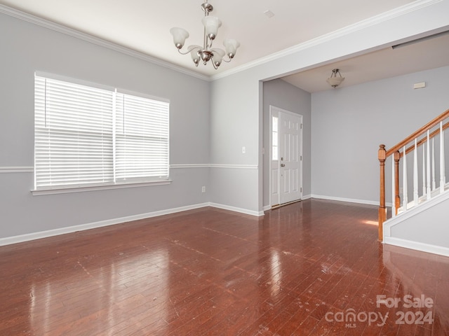 interior space with a notable chandelier, dark hardwood / wood-style floors, and ornamental molding